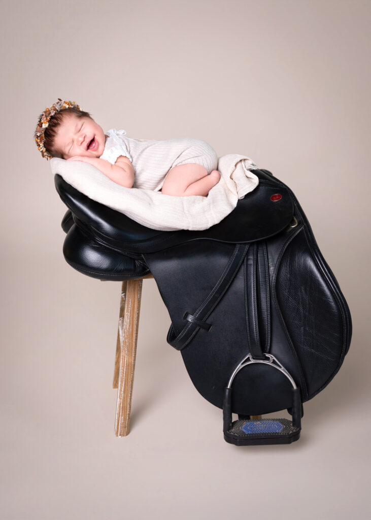 Neugeborenes Baby auf einem Pferdesattel beim kreativen Fotoshooting in Wiesbaden