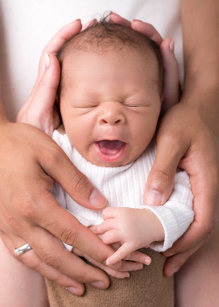 Neugeborenes Baby liegt geborgen in den Händen der Eltern beim Shooting in Mainz